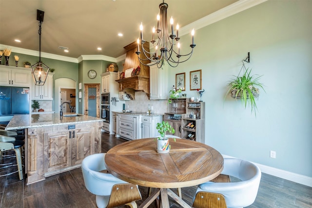 dining area featuring sink, a chandelier, dark hardwood / wood-style floors, and ornamental molding