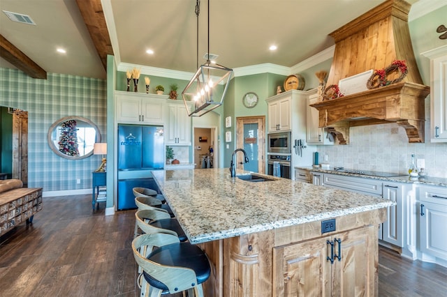 kitchen with appliances with stainless steel finishes, sink, pendant lighting, dark hardwood / wood-style floors, and an island with sink