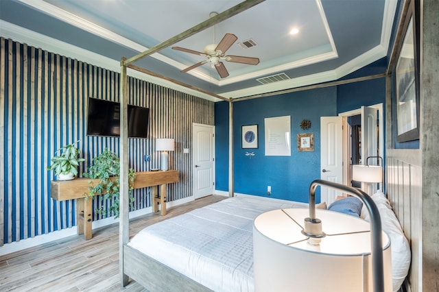 bedroom with a tray ceiling, light hardwood / wood-style flooring, ceiling fan, and crown molding