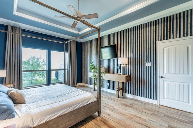 bedroom featuring light hardwood / wood-style floors, a raised ceiling, ceiling fan, and crown molding