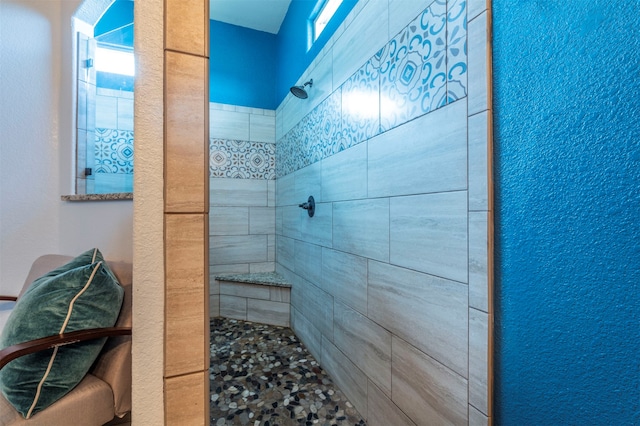 bathroom featuring a tile shower and a healthy amount of sunlight