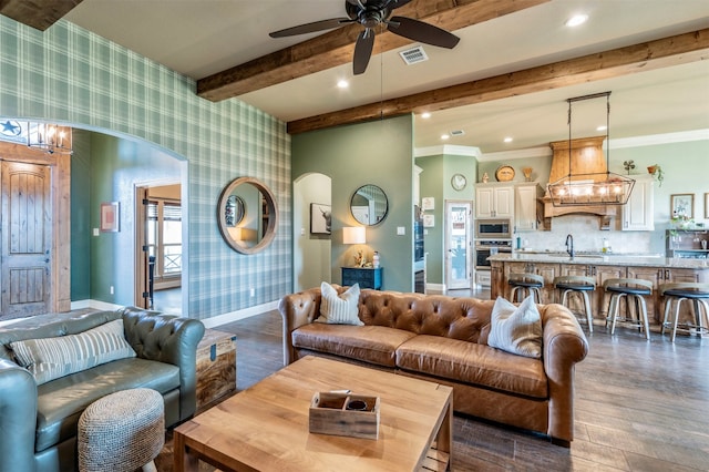 living room featuring ceiling fan with notable chandelier, sink, crown molding, dark hardwood / wood-style floors, and beam ceiling