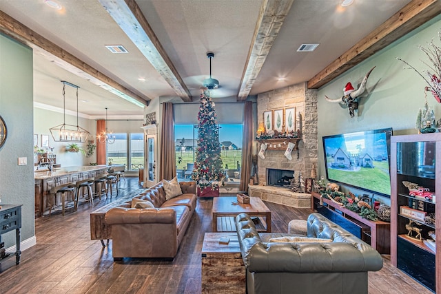 living room with hardwood / wood-style flooring, a notable chandelier, a fireplace, and beamed ceiling