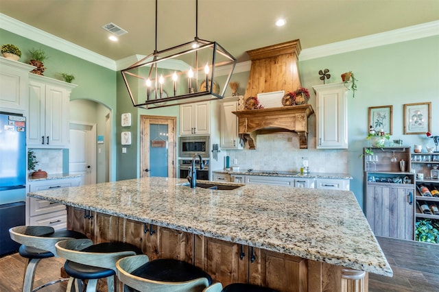 kitchen with light stone countertops, appliances with stainless steel finishes, dark wood-type flooring, a spacious island, and decorative light fixtures