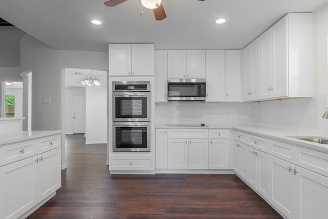 kitchen featuring white cabinetry, sink, dark wood-type flooring, stainless steel appliances, and tasteful backsplash