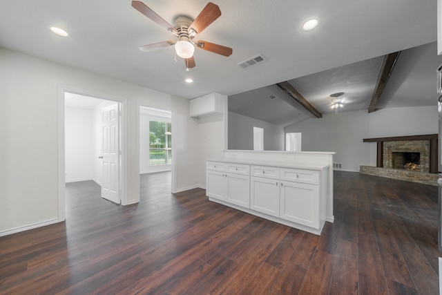 unfurnished living room featuring a fireplace, lofted ceiling with beams, ceiling fan, and dark wood-type flooring