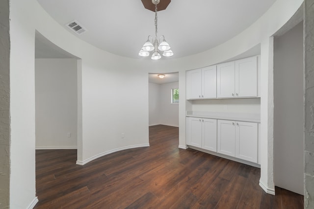 unfurnished dining area with dark hardwood / wood-style floors and an inviting chandelier