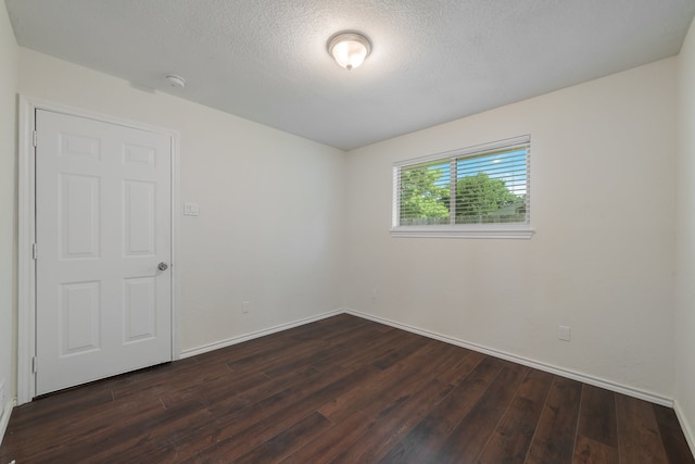 unfurnished room with a textured ceiling and dark hardwood / wood-style floors