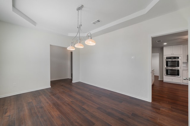 unfurnished room with dark wood-type flooring and a tray ceiling