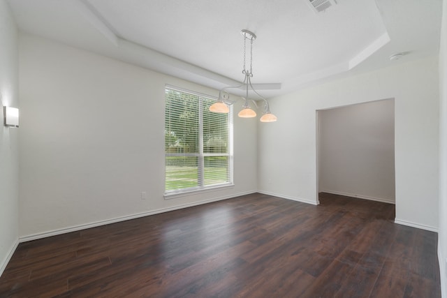 unfurnished room featuring a raised ceiling, dark hardwood / wood-style flooring, and an inviting chandelier