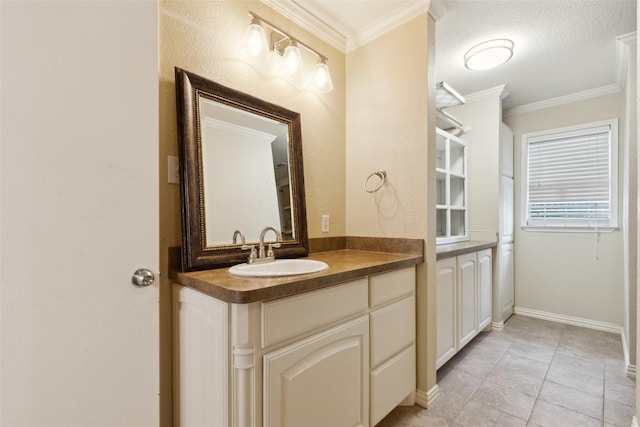 bathroom with baseboards, tile patterned floors, vanity, and crown molding