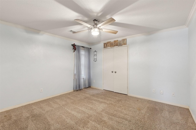 empty room with baseboards, ceiling fan, a textured ceiling, crown molding, and carpet flooring