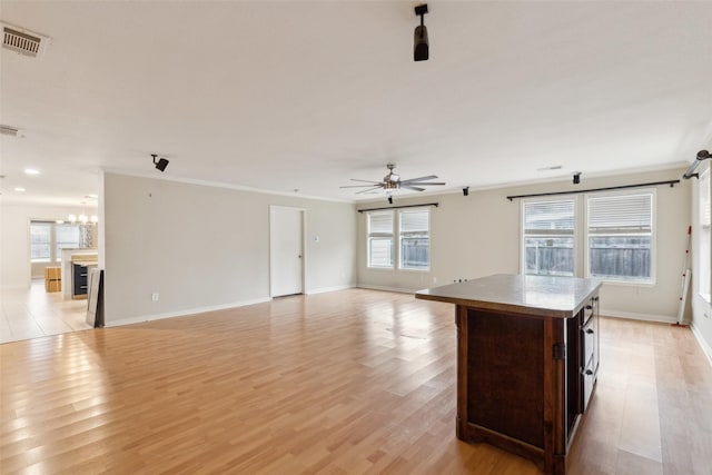 kitchen featuring a center island, light wood finished floors, visible vents, ornamental molding, and open floor plan