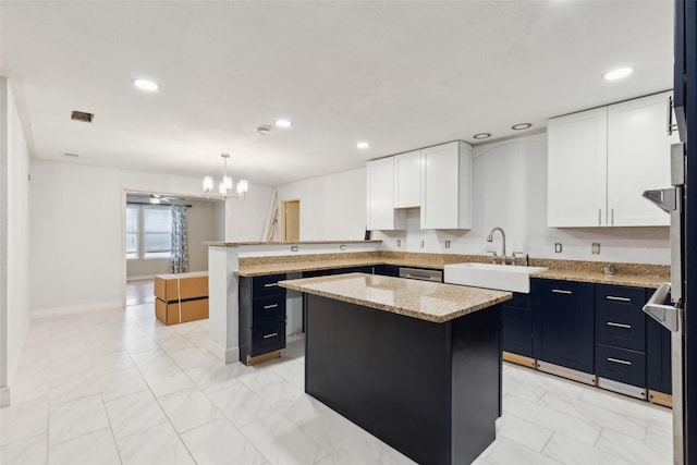 kitchen with light stone counters, a sink, white cabinetry, hanging light fixtures, and a center island