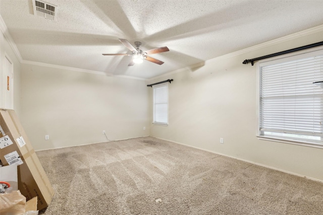 carpeted empty room featuring visible vents, a textured ceiling, and ornamental molding