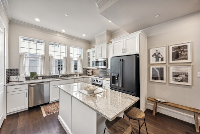 kitchen with white cabinets, a kitchen island, sink, and appliances with stainless steel finishes