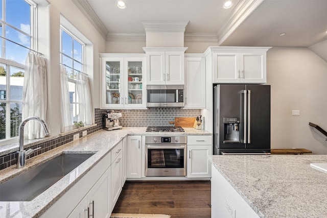 kitchen with dark wood-type flooring, white cabinets, sink, light stone countertops, and appliances with stainless steel finishes