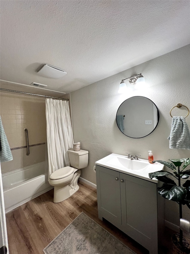 full bathroom with a textured ceiling, vanity, shower / bath combo with shower curtain, hardwood / wood-style flooring, and toilet