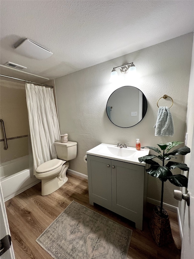 full bathroom featuring shower / bath combination with curtain, a textured ceiling, toilet, vanity, and hardwood / wood-style flooring