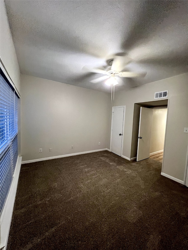 unfurnished bedroom with a textured ceiling, dark carpet, and ceiling fan