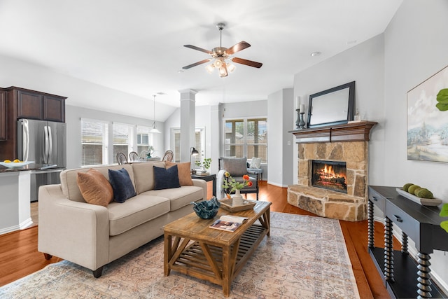 living room featuring hardwood / wood-style floors, vaulted ceiling, ceiling fan, ornate columns, and a fireplace