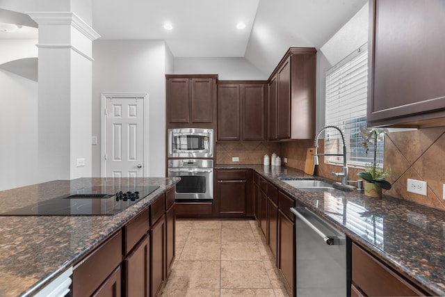 kitchen featuring ornate columns, sink, stainless steel appliances, backsplash, and dark stone countertops