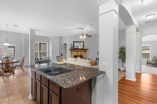 kitchen with plenty of natural light, black electric cooktop, a fireplace, dark brown cabinets, and light hardwood / wood-style floors