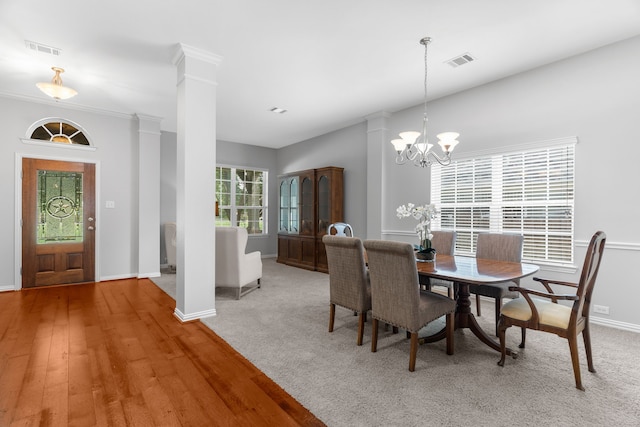 dining space featuring hardwood / wood-style floors, a notable chandelier, ornamental molding, and decorative columns