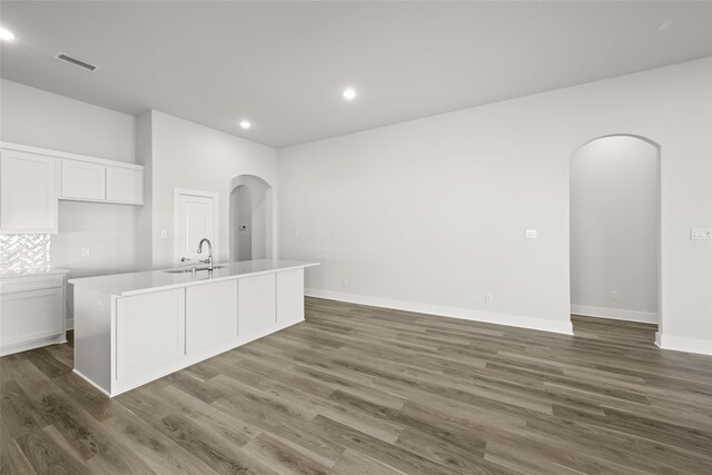 kitchen featuring dark hardwood / wood-style flooring, white cabinetry, a center island with sink, and sink