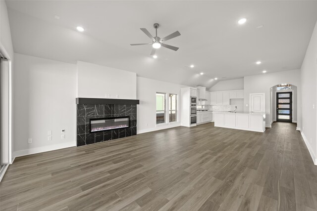 unfurnished living room with lofted ceiling, dark wood-type flooring, sink, ceiling fan, and a premium fireplace