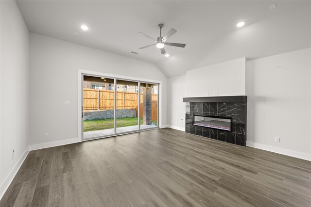 unfurnished living room with a high end fireplace, hardwood / wood-style flooring, ceiling fan, and lofted ceiling