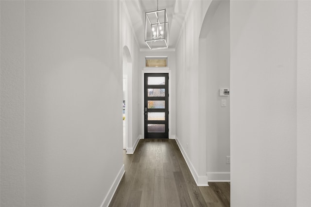 hall with a notable chandelier, dark hardwood / wood-style flooring, and ornamental molding