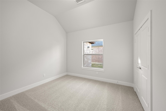 carpeted empty room featuring vaulted ceiling