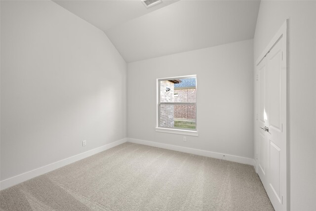 carpeted empty room featuring vaulted ceiling