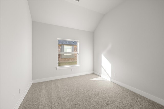 carpeted spare room with vaulted ceiling