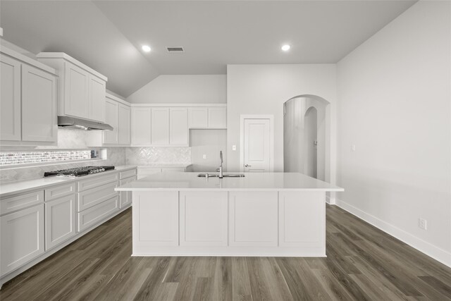 kitchen featuring sink, stainless steel gas cooktop, lofted ceiling, a center island with sink, and white cabinets