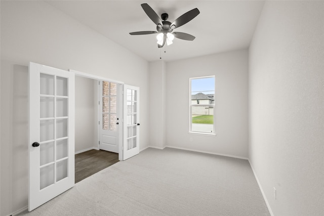 spare room featuring dark colored carpet, ceiling fan, and french doors