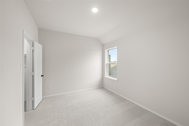 empty room with vaulted ceiling and light colored carpet