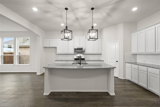 kitchen with decorative light fixtures, light stone counters, and appliances with stainless steel finishes