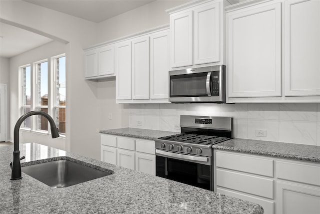 kitchen featuring light stone countertops, sink, white cabinetry, and stainless steel appliances