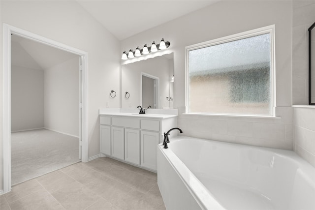 bathroom with vanity, a washtub, and lofted ceiling