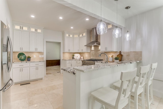 415 Featherston St, Cleburne, TX 76033 - kitchen featuring wall chimney exhaust hood, stainless steel fridge with ice dispenser, a peninsula, backsplash, and light stone counters