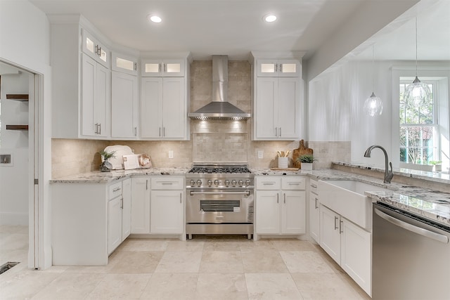 kitchen with white cabinetry, wall chimney exhaust hood, decorative light fixtures, and appliances with stainless steel finishes