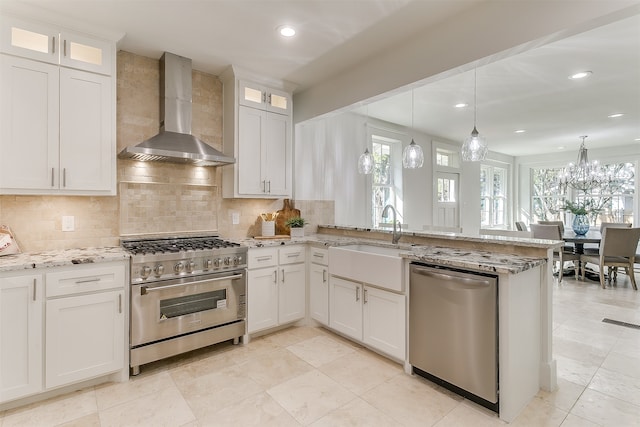 kitchen featuring white cabinets, pendant lighting, wall chimney range hood, and appliances with stainless steel finishes