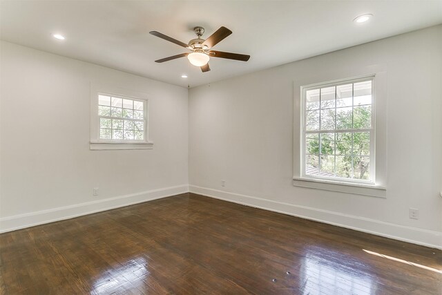 spare room with plenty of natural light, ceiling fan, and dark wood-type flooring