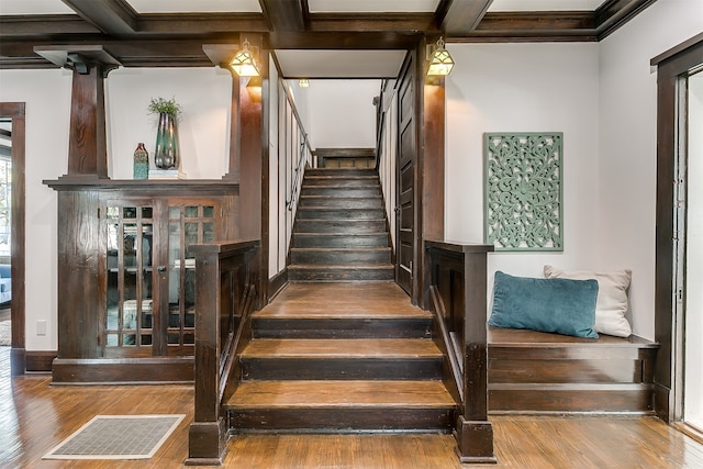 stairs featuring beam ceiling, hardwood / wood-style flooring, and coffered ceiling