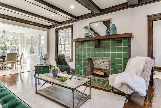 sitting room with a tiled fireplace, a wealth of natural light, beamed ceiling, and wood-type flooring