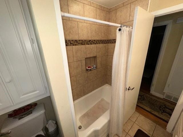 bathroom with tile patterned floors, shower / bath combination with curtain, and toilet