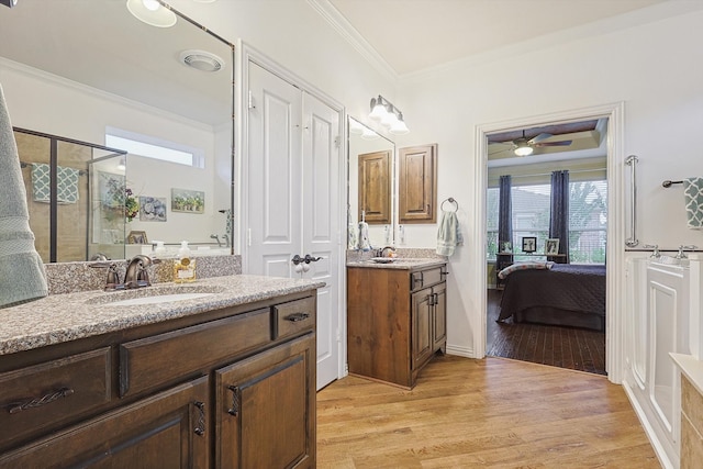 bathroom with vanity, ceiling fan, crown molding, a shower with door, and hardwood / wood-style flooring