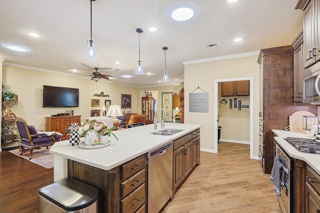 kitchen featuring crown molding, sink, light wood-type flooring, an island with sink, and stainless steel appliances